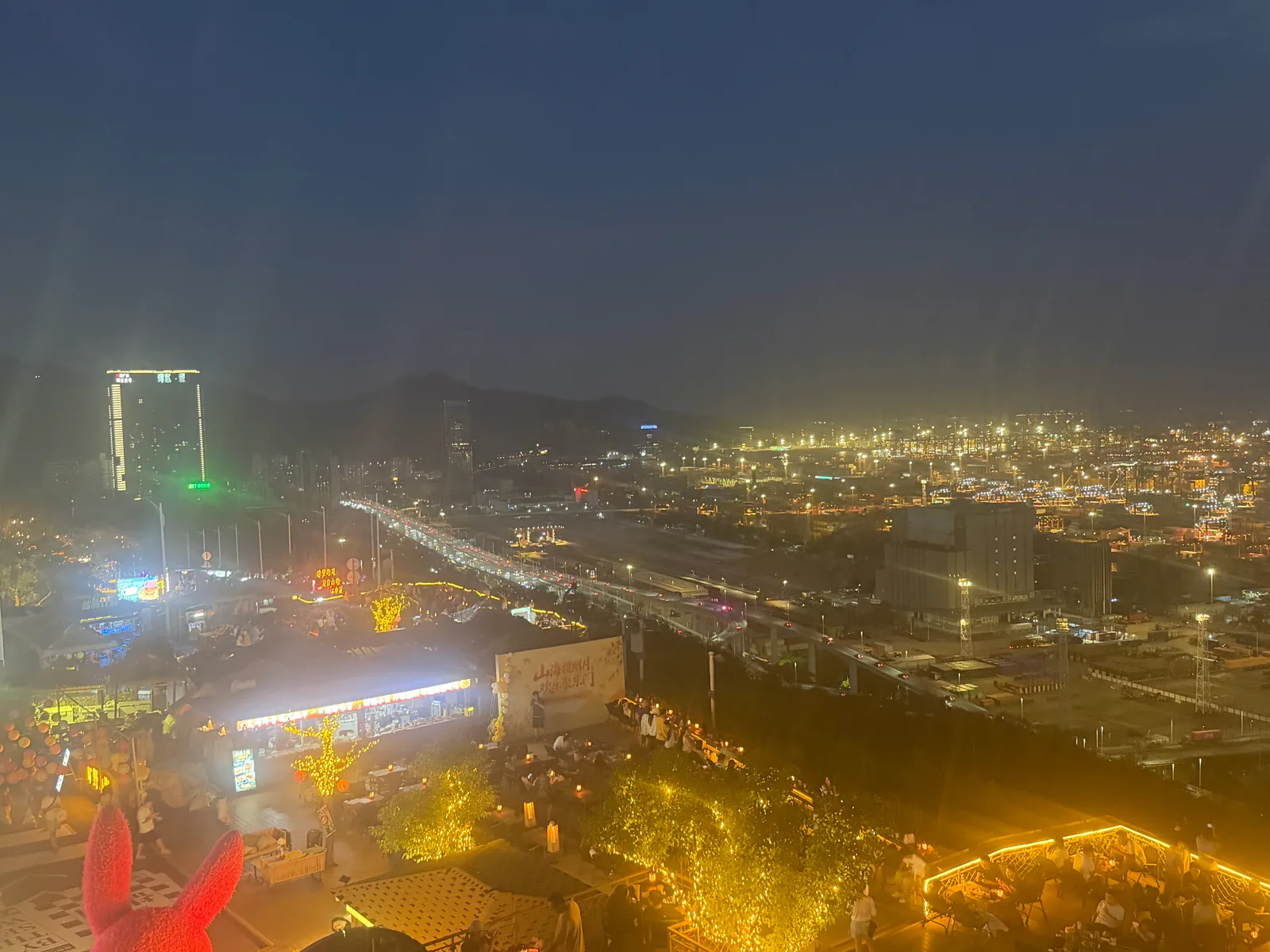 盐港夜市灯串、人群与远处灯火通明的码头